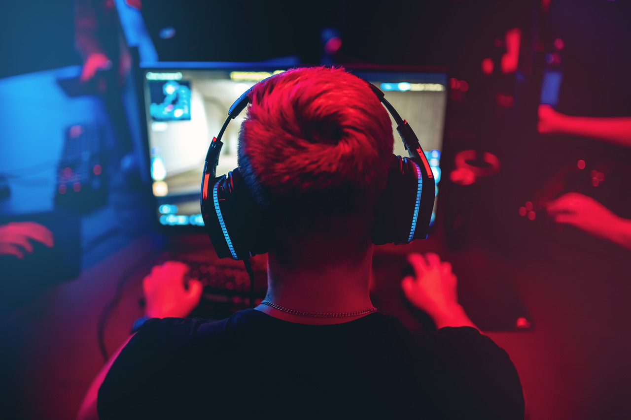 Professional gamer playing online games tournaments pc computer with headphones, Blurred red and blue background